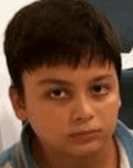a young boy with a serious look on his face is looking at the camera .