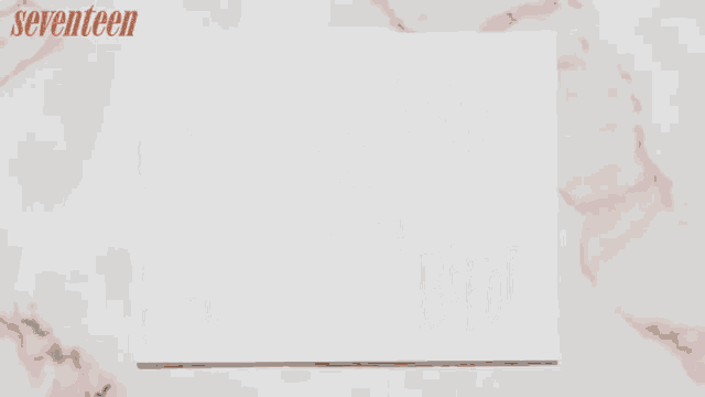 a person with red nails is writing on a piece of paper
