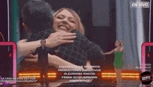 a woman is hugging a man in front of a sign that says " en vivo "