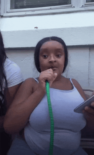 a woman in a white tank top smoking a hookah