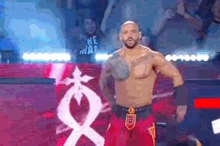 a man is standing on a stage in front of a crowd wearing red shorts .
