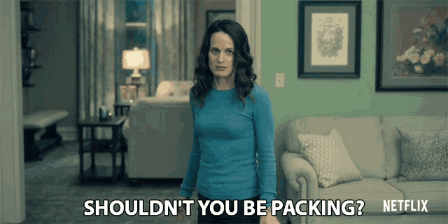 a woman is standing in a living room with the words shouldn 't you be packing netflix
