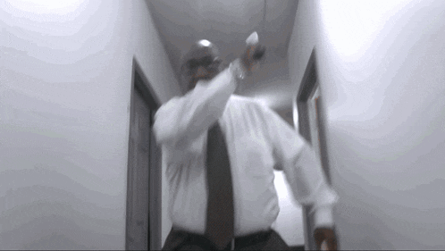 a man in a white shirt and black tie is dancing in a hallway