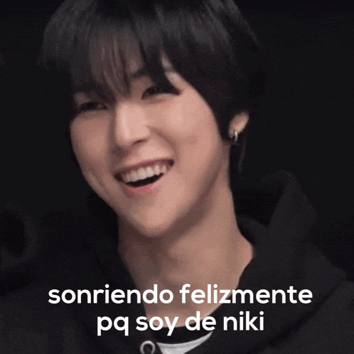 a young man is smiling with the words sonriendo felizmente pq soy de niki behind him