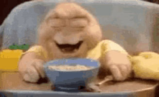 a stuffed animal is sitting in a high chair eating a bowl of cereal .