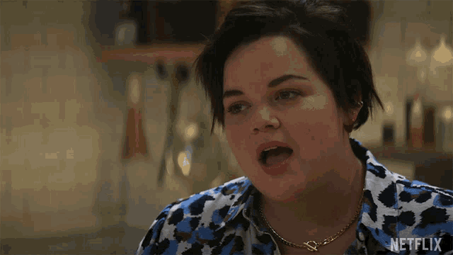 a woman wearing a leopard print shirt and a necklace with netflix written on the bottom right