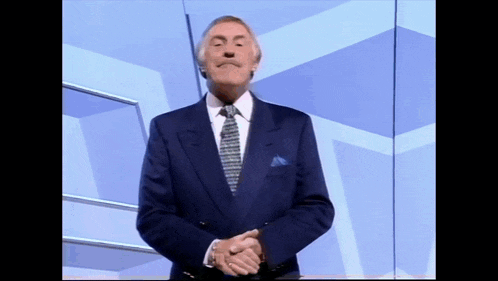 a man in a suit and tie is standing with his hands folded