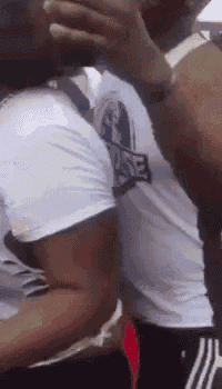 a man in a white shirt is covering his face with his hand while another man looks on .
