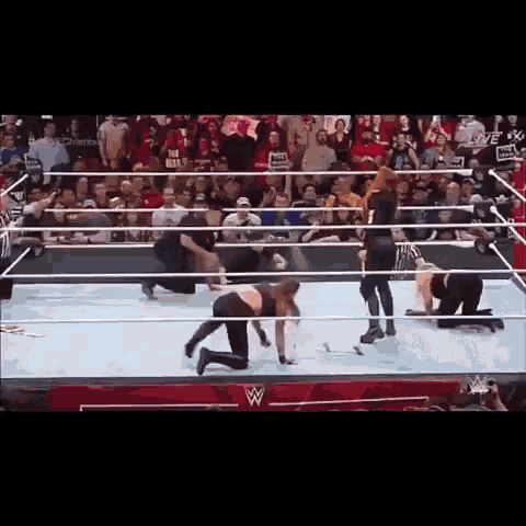 a woman is kneeling in a wrestling ring while a referee looks on .