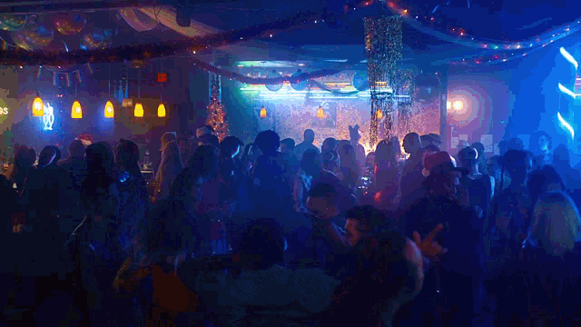 a large crowd of people are dancing in a club with a sign that says ' s ' on it