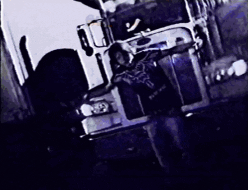 a black and white photo of a man standing in front of a white truck