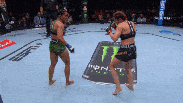 two women are fighting in a ring with a monster energy can in the middle