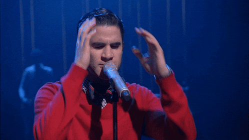 a man is singing into a microphone with his hands outstretched
