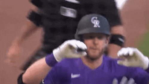 a baseball player wearing a purple jersey and a black helmet is being hugged by his teammates .