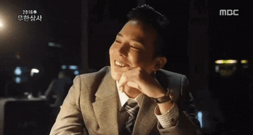 a man in a suit and tie is smiling with his hand on his chin ..