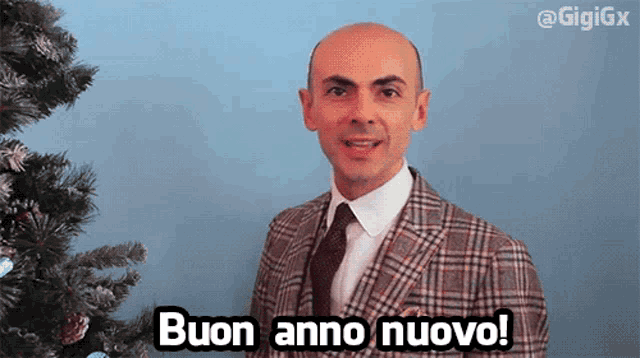 a man in a suit and tie says buon anno nuovo in front of a christmas tree