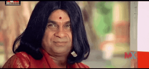 a man with long hair and a red bindi on his forehead looks at the camera .