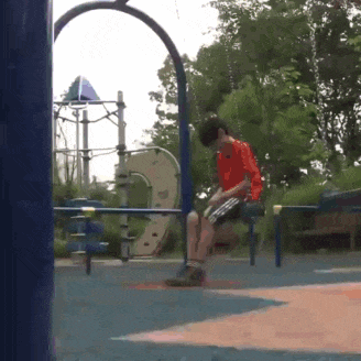 a boy in a red shirt sits on a swing in a park