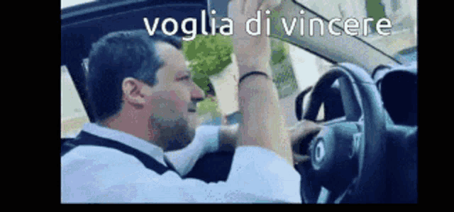 a man is driving a car and the words voglia di vincere are on the screen
