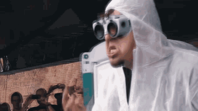 a man wearing a white suit and goggles is standing in front of a crowd of people .