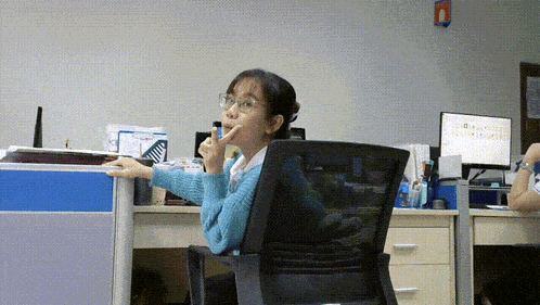 a woman is sitting at a desk with a computer monitor that says ' abc ' on it
