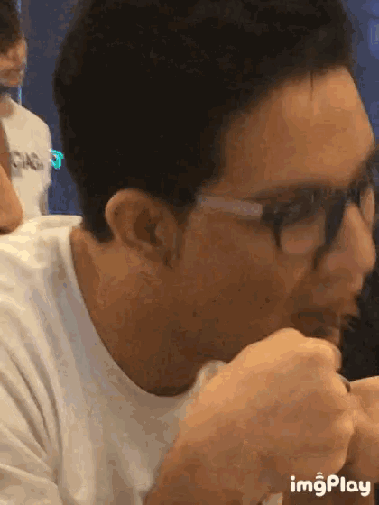 a man wearing glasses is eating a piece of meat