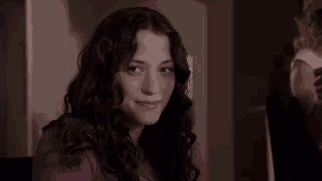 a woman in a purple shirt is smiling for the camera