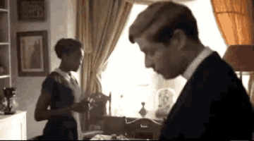 a man and a woman are standing in front of a window in a living room .