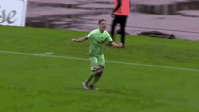 a soccer player in a green jersey celebrates a goal on the field
