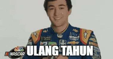 a man in a nascar uniform is smiling and holding a watch with the words ulang tahun written below him .
