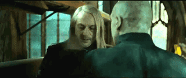 a man with long blonde hair is standing next to another man