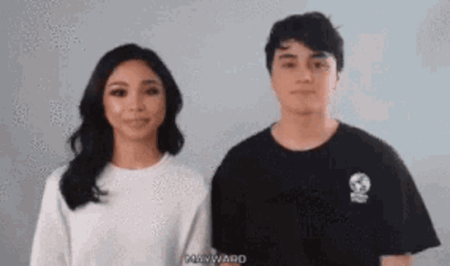 a man and a woman are standing next to each other and the man is wearing a black shirt with a skull on it