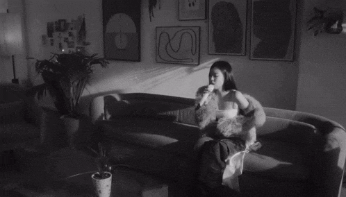 a woman in a fur coat stands in front of a couch