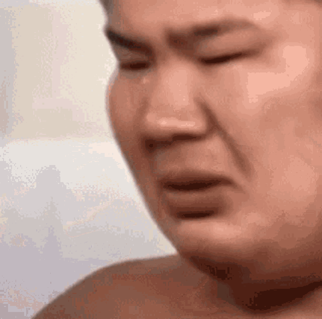 a close up of a man 's face with his eyes closed and a tear running down his cheek .