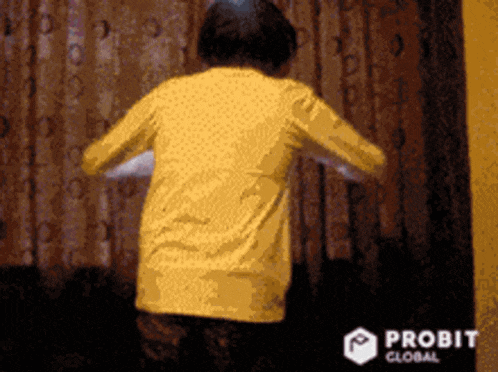 a person in a yellow shirt is dancing in front of a curtain with the word probit global on the bottom