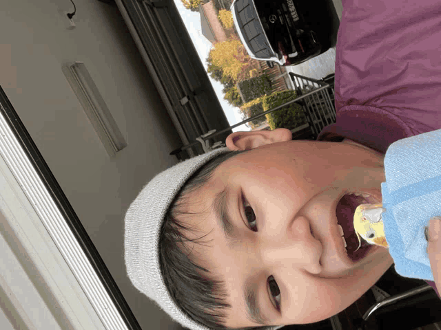 a boy wearing a hat holds a bird in his mouth with a license plate that says ' a ' on it