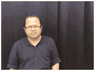 a man wearing glasses and a blue striped shirt is making a funny face .
