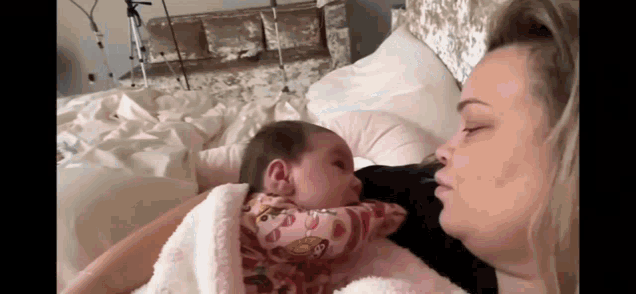 a woman is holding a baby in her arms and kissing it on the cheek .