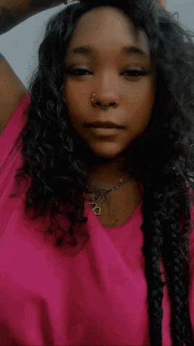 a woman in a pink shirt has a nose ring and braids