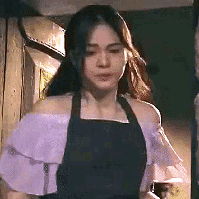 a woman wearing an apron is holding a glass of wine in her hand