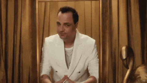 a man in a white jacket is looking at himself in a mirror