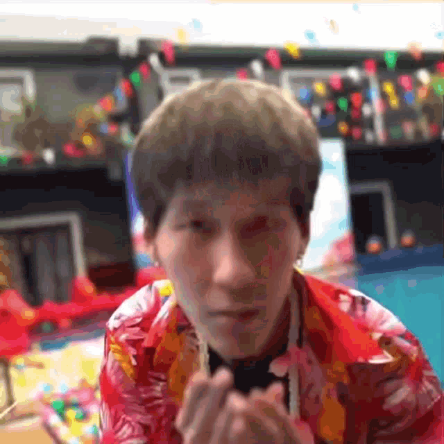 a man wearing a red shirt is making a heart shape with his hands .