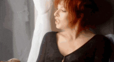 a woman with red hair is sitting in front of a window with her eyes closed .
