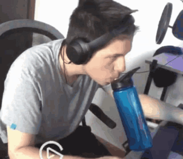 a man wearing headphones drinking from a blue bottle