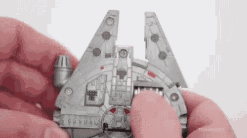 a person is holding a model of a star wars millennium falcon .