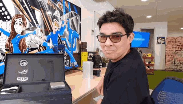 a man wearing glasses is sitting in front of a box that says rog