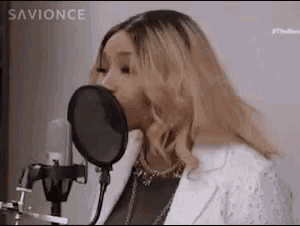 a woman is singing into a microphone with a pop filter .