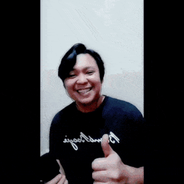 a man giving a thumbs up wearing a black shirt that says ' good time ' on it