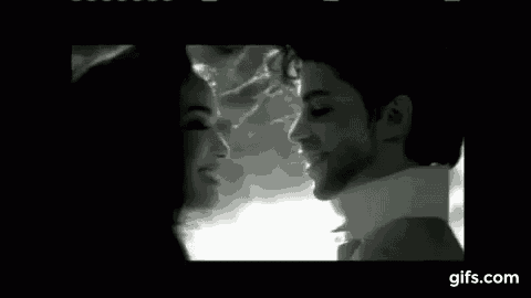 a black and white photo of a man and a woman looking at each other .