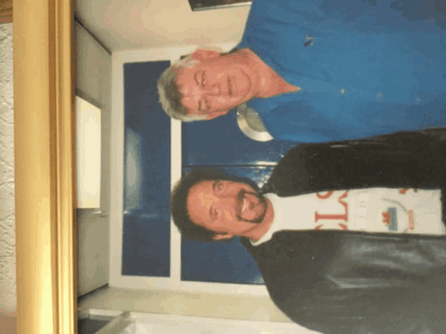 two men are posing for a picture and one is wearing a t-shirt that says ' columbia '